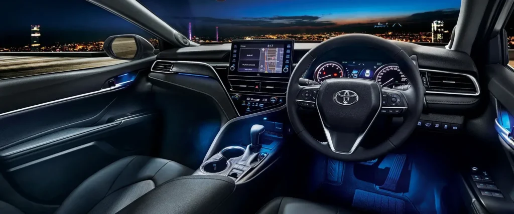 Toyota Camry interior dashboard view with touchscreen display and city lights visible through windshield