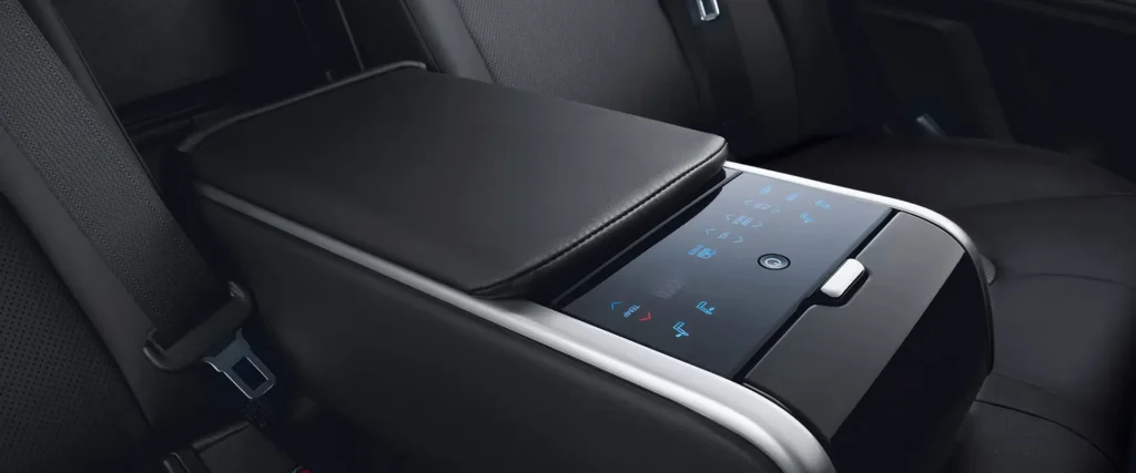 Luxury rear seat armrest with touchscreen controls and climate settings in premium sedan interior cabin