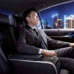 A man enjoying spacious rear seating area with urban nighttime cityscape visible through glass