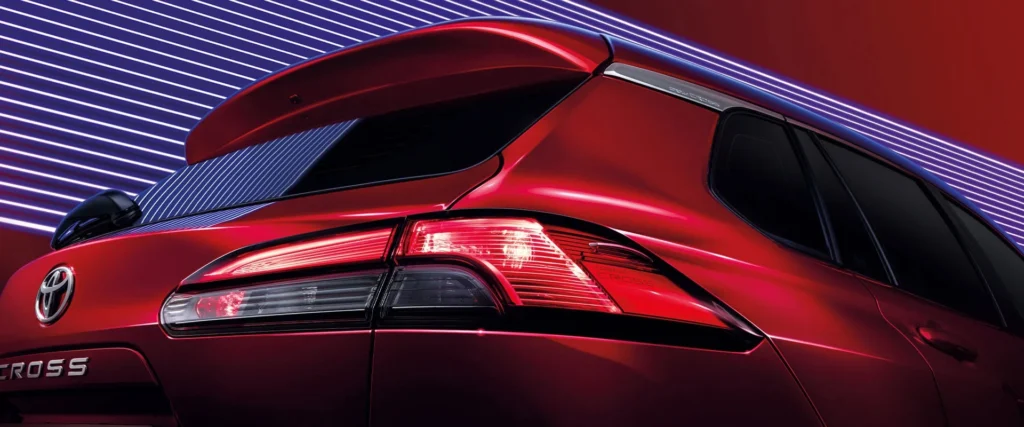 Toyota Corolla Cross rear taillight detail with LED technology and dramatic red illumination against dark background