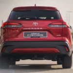 Red Toyota Corolla Cross rear view on highway showing SUV proportions and Cross badging with infrastructure