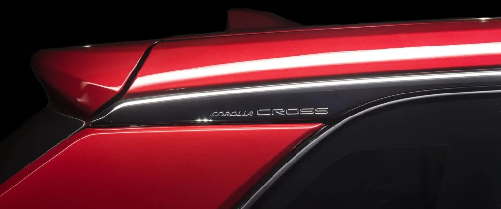 Toyota Corolla Cross side body panel detail showing red paint finish and Cross model nameplate lettering