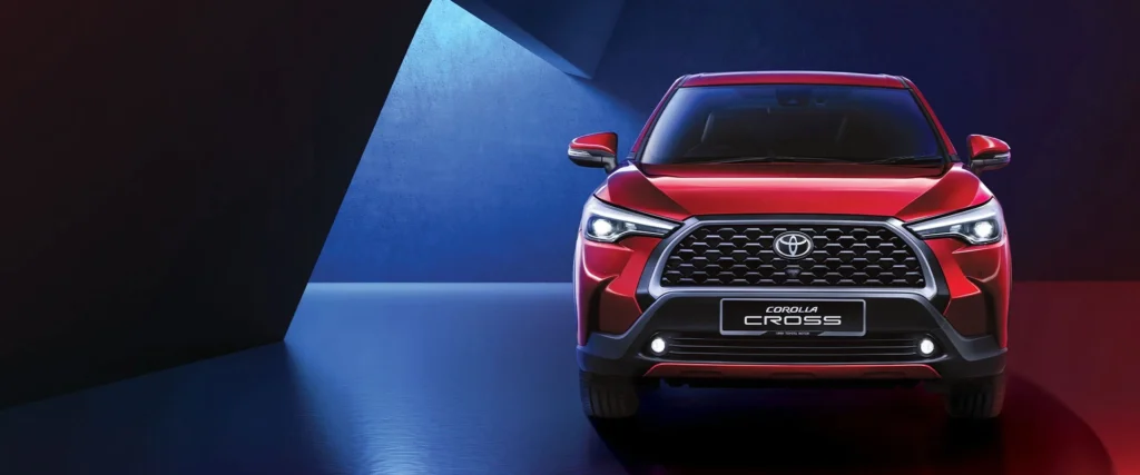 Red Toyota Corolla Cross front view in studio setting with dramatic blue lighting and bold grille design