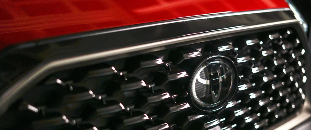 Close-up detail of Toyota Corolla Cross front grille showing hexagonal mesh pattern and chrome brand emblem
