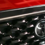 Close-up detail of Toyota Corolla Cross front grille showing hexagonal mesh pattern and chrome brand emblem