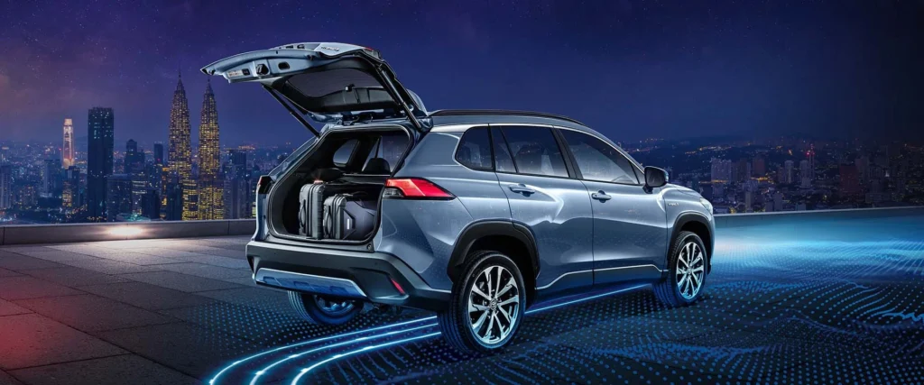 Toyota Corolla Cross Hybrid Electric with open tailgate showing cargo space against Kuala Lumpur city skyline