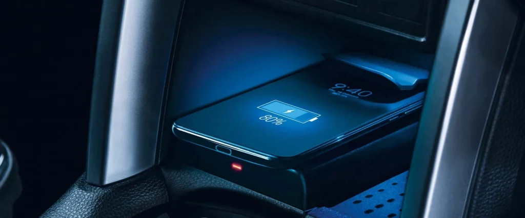Toyota Corolla Cross Hybrid Electric wireless charging pad with smartphone displaying battery level and blue illumination