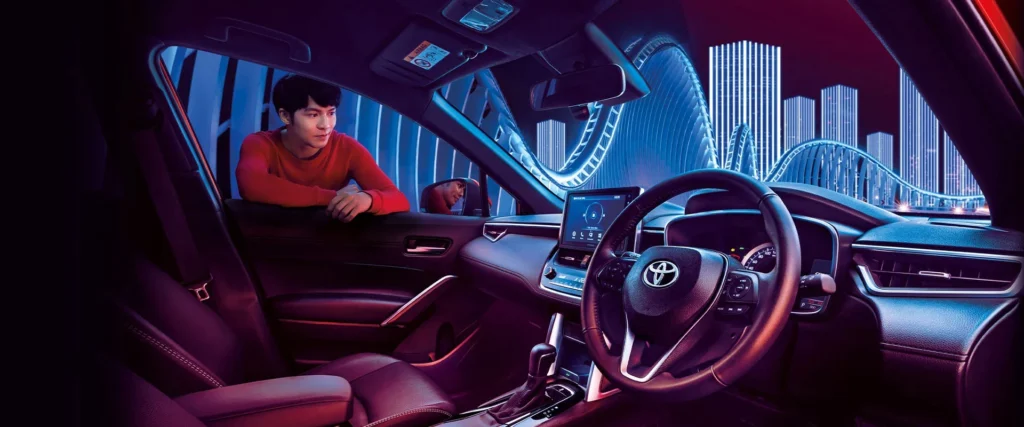 Spacious Toyota Corolla Cross dashboard featuring ambient lighting and modern urban architecture background scenery