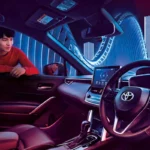 Spacious Toyota Corolla Cross dashboard featuring ambient lighting and modern urban architecture background scenery