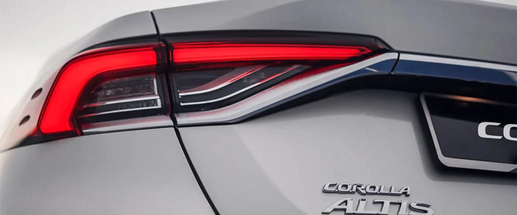 Close-up detail of Toyota Corolla rear taillight with LED technology and Corolla Altis badge on white paint