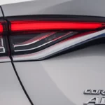 Close-up detail of Toyota Corolla rear taillight with LED technology and Corolla Altis badge on white paint