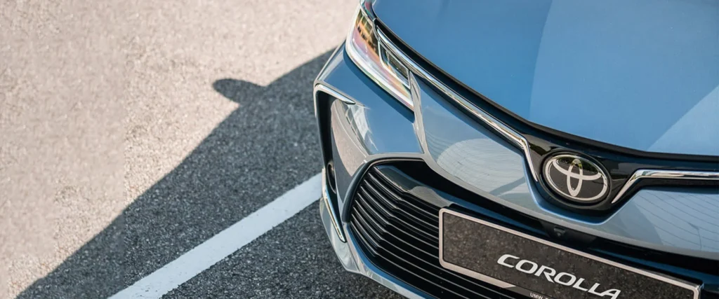 Toyota Corolla front grille detail showing chrome logo emblem and license plate mount with premium finish