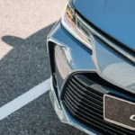 Toyota Corolla front grille detail showing chrome logo emblem and license plate mount with premium finish