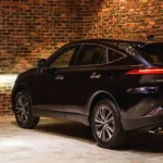 Black Toyota Harrier SUV parked in industrial garage with exposed brick walls and sleek alloy wheel design