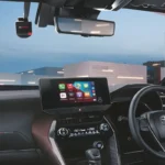 Toyota Harrier interior with driver using multimedia system displaying various app icons and navigation interface