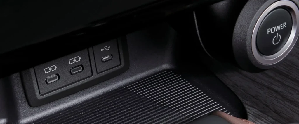 Close-up of Toyota Harrier dashboard featuring multiple charging ports and engine start button with textured trim