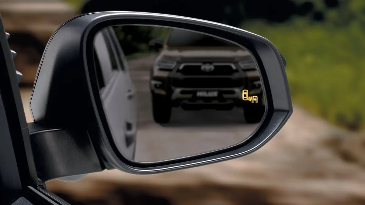 Toyota Hilux side mirror view showing Blind Spot Monitor with yellow warning indicator