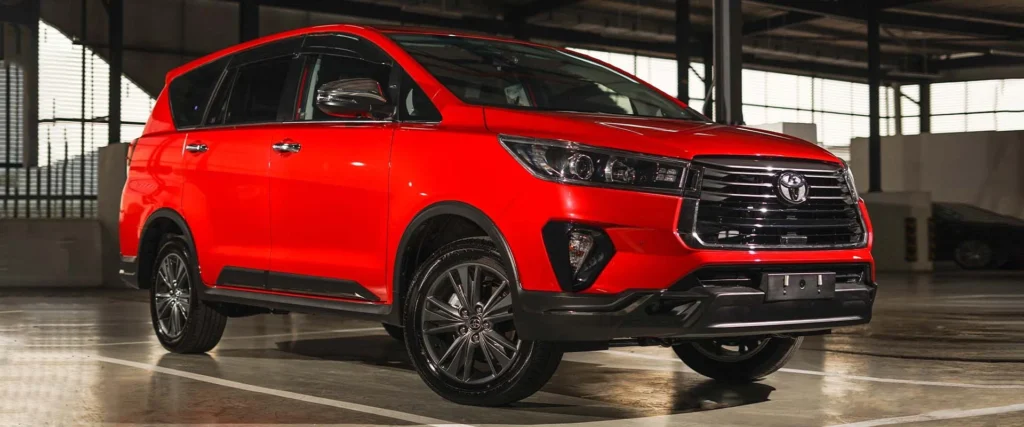 Red Toyota Innova parked in industrial setting showcasing bold exterior styling and premium wheel design