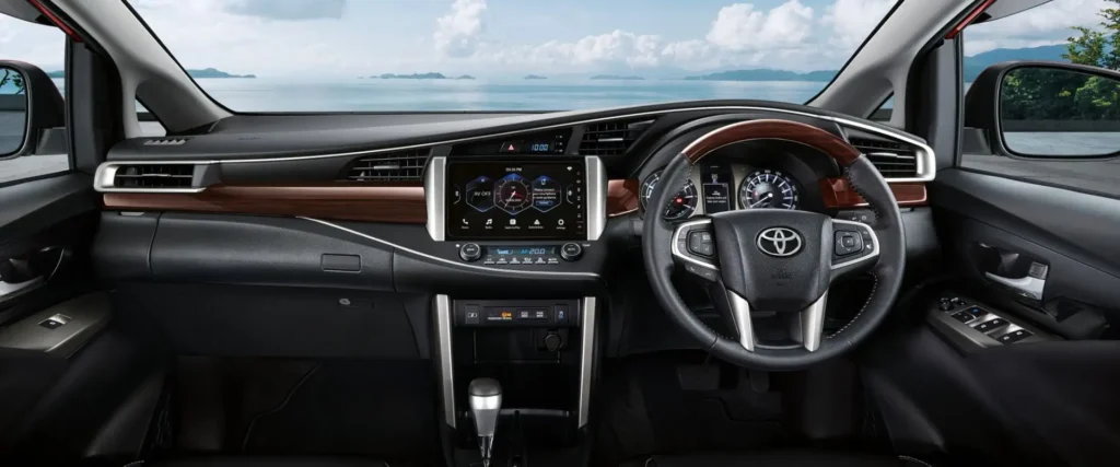 Toyota Innova dashboard and steering wheel with touchscreen infotainment system and scenic ocean backdrop