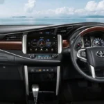 Toyota Innova dashboard and steering wheel with touchscreen infotainment system and scenic ocean backdrop