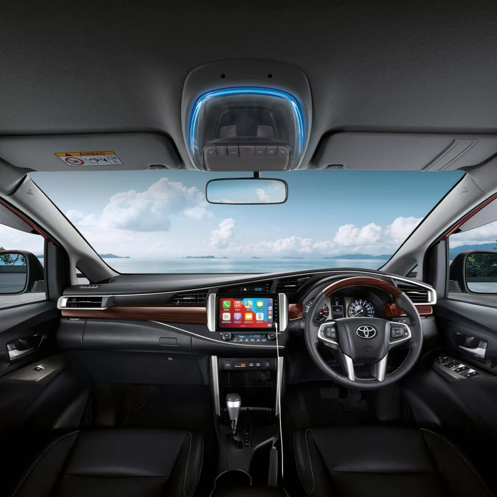 Toyota Innova dashboard and steering wheel with touchscreen infotainment system and scenic ocean backdrop