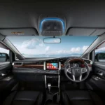 Toyota Innova dashboard and steering wheel with touchscreen infotainment system and scenic ocean backdrop