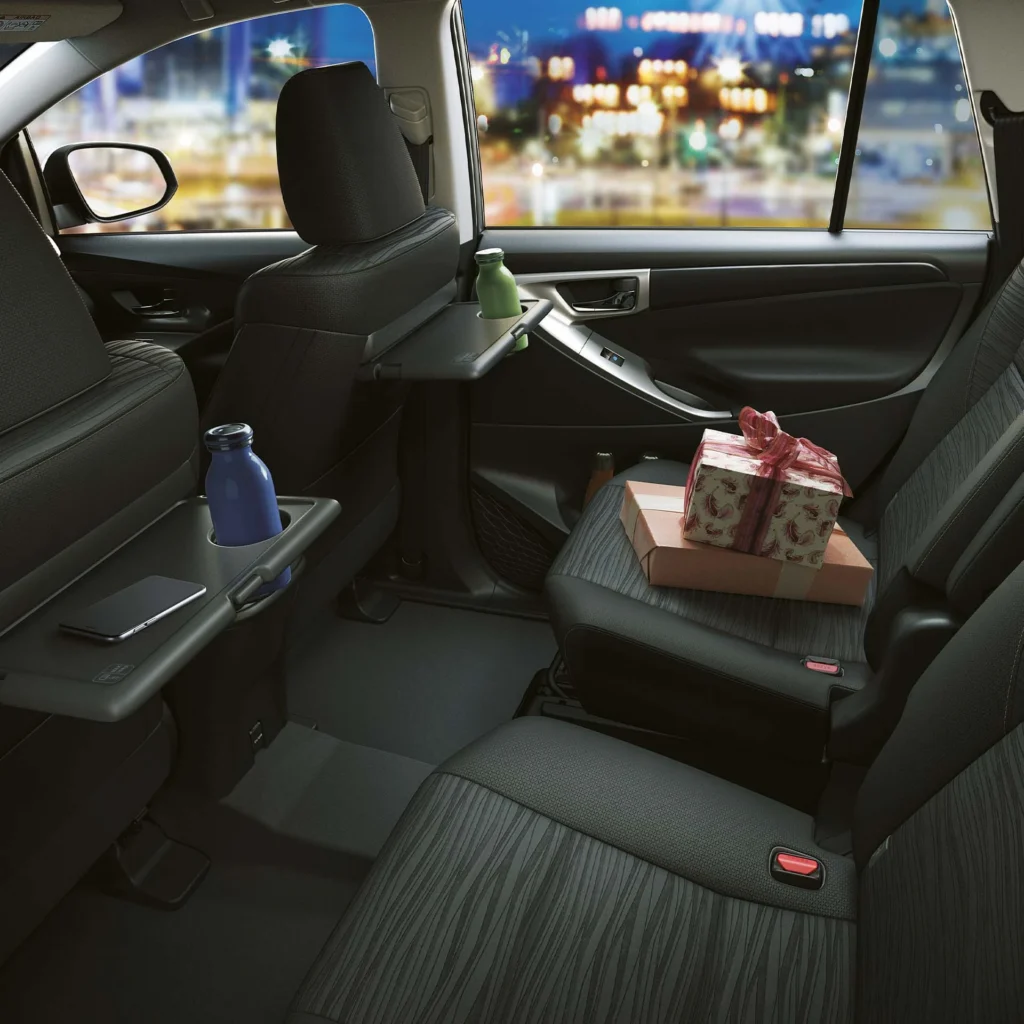 Toyota Innova spacious second-row interior featuring reclining seats, armrest with cup holders, and city view
