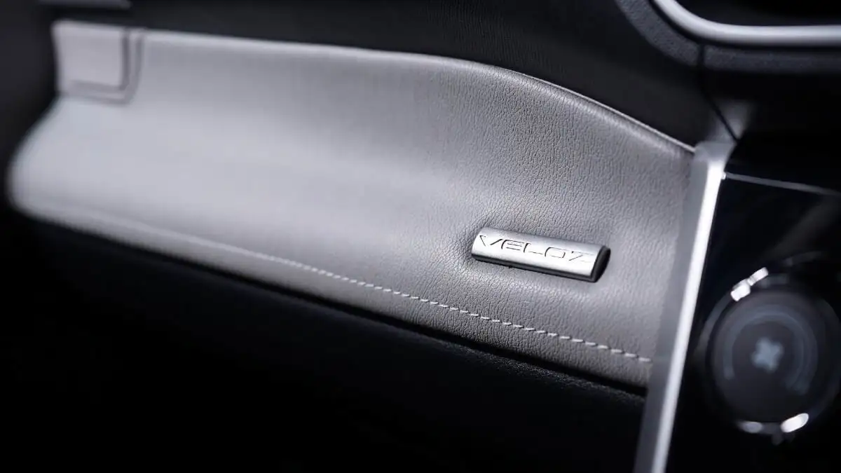 Toyota Veloz interior dashboard detail featuring two-tone soft pad design with embossed nameplate badge