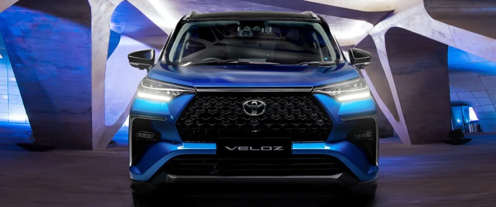 Blue Toyota Veloz front view with LED headlights in modern showroom with dramatic architectural lighting