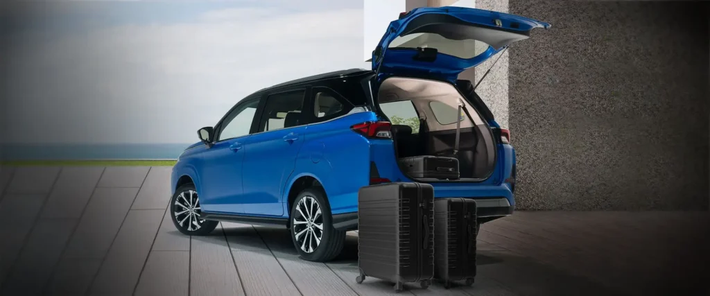 Blue Toyota Veloz with open tailgate displaying cargo space and travel luggage on concrete surfac