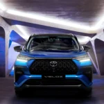 Blue Toyota Veloz SUV front view with LED headlights in modern showroom with dramatic architectural lighting