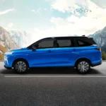 Toyota Veloz blue vehicle side angle on mountain road with dramatic rocky cliffs and cloudy sky backdrop