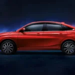 Red Toyota Vios sedan side profile with dramatic studio lighting showcasing sleek modern design and alloy wheels