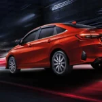 Toyota Vios red car back angle with illuminated taillights driving through city environment at night