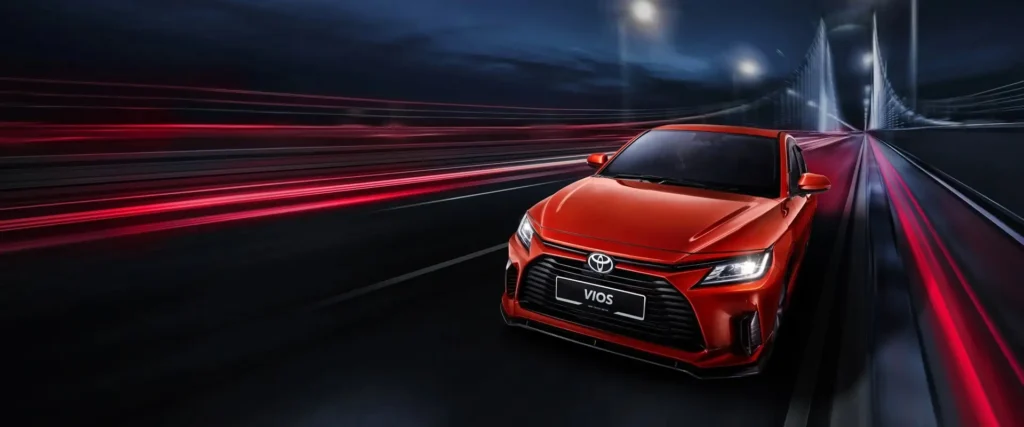 Toyota Vios red car front facade with headlights on showing grille design in dynamic night scene