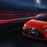 Toyota Vios red car front facade with headlights on showing grille design in dynamic night scene