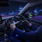 Driver in Toyota Vios interior with touchscreen navigation display while driving through city at night