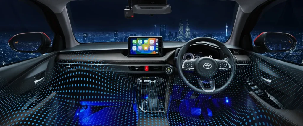 Toyota Vios interior dashboard with blue ambient lighting and touchscreen display overlooking city skyline