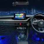 Toyota Vios interior dashboard with blue ambient lighting and touchscreen display overlooking city skyline