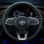 Car dashboard showing Toyota Vios steering wheel controls and modern gauge cluster with digital readouts