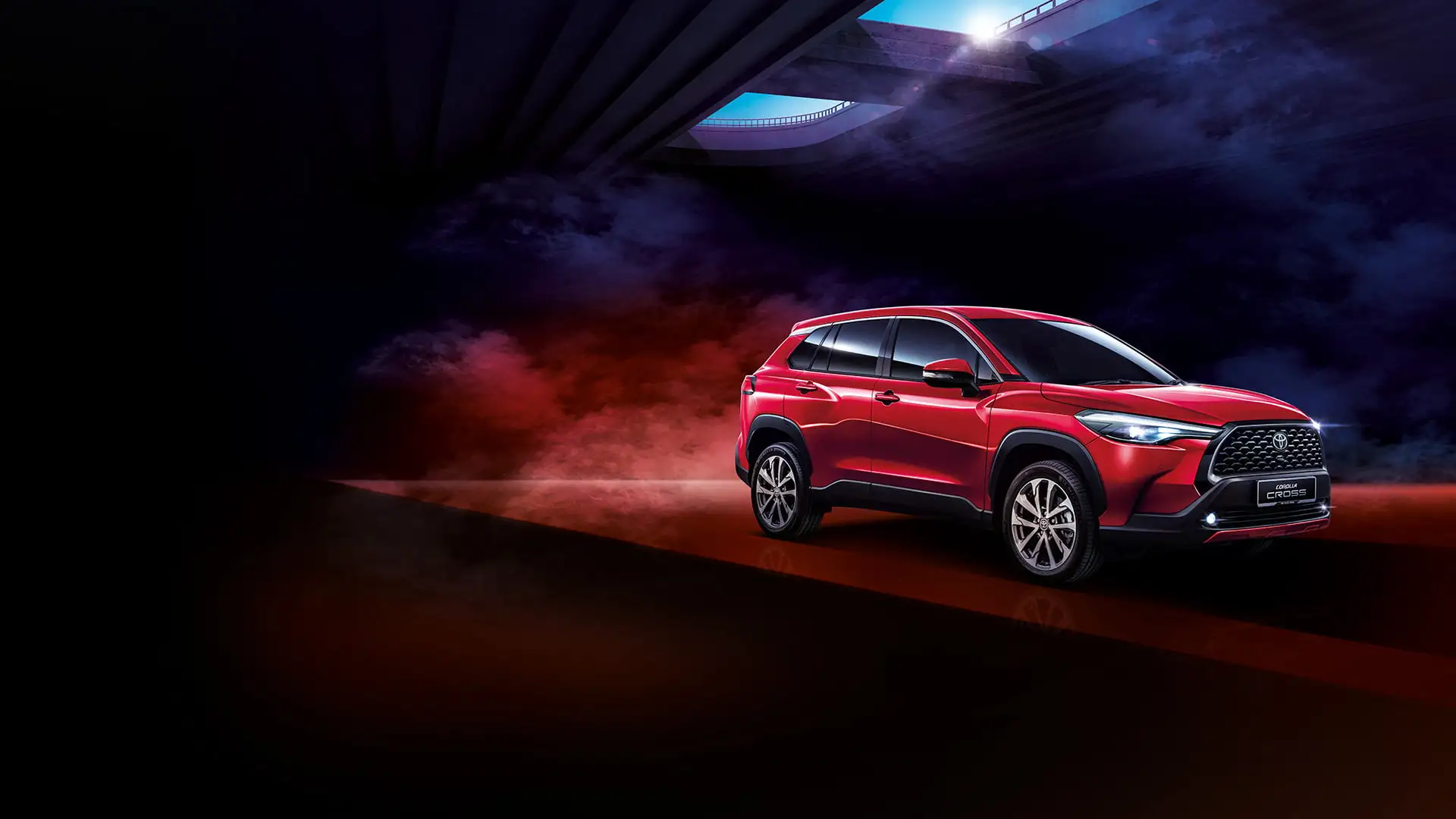 Red Toyota Corolla Cross positioned on dramatic dark surface with colorful smoke and futuristic lighting effects