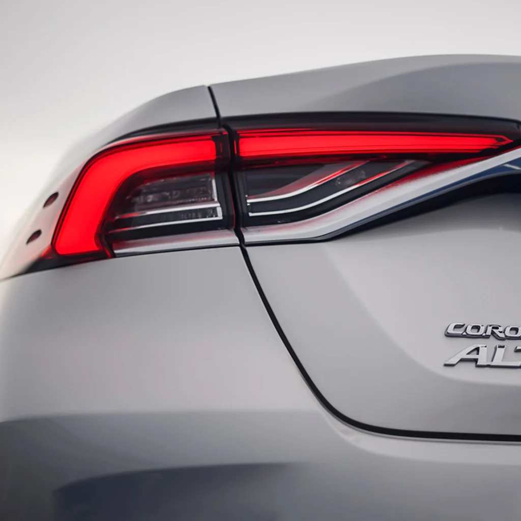 Close-up detail of Toyota Corolla rear taillight with LED technology and Corolla Altis badge on white paint