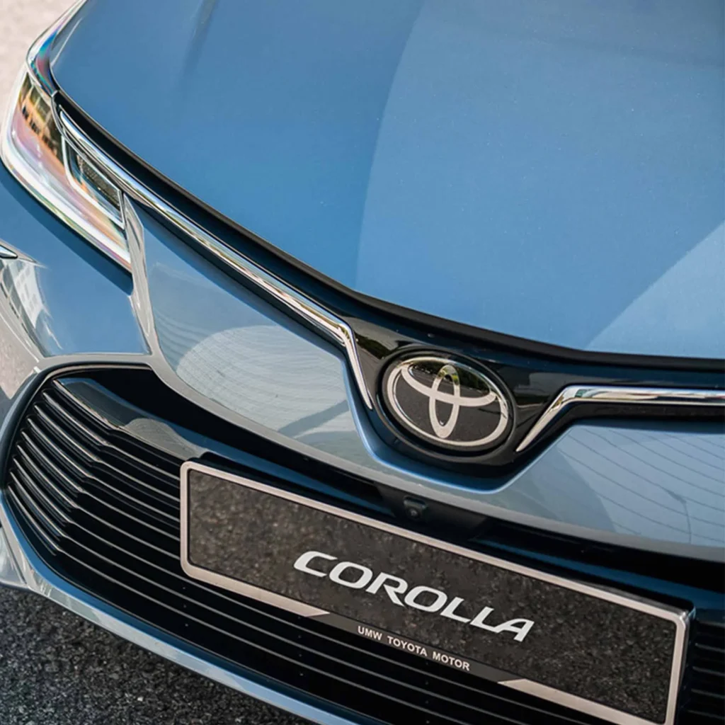 Toyota Corolla front grille detail showing chrome logo emblem and license plate mount with premium finish