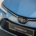 Toyota Corolla front grille detail showing chrome logo emblem and license plate mount with premium finish