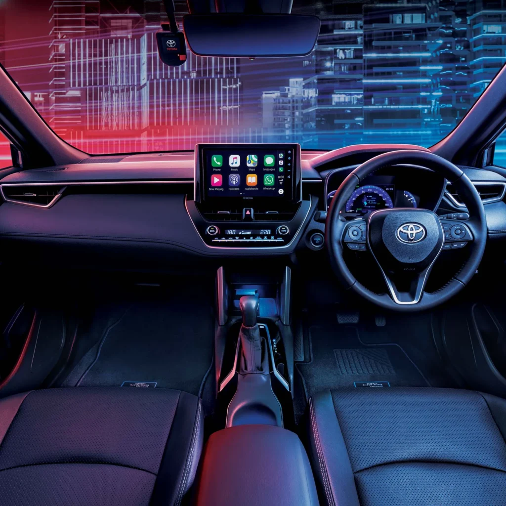 Toyota Corolla Cross Hybrid Electric interior dashboard with smartphone connectivity and futuristic city backdro