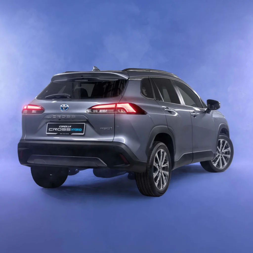 Toyota Corolla Cross Hybrid Electric rear three-quarter view in futuristic studio with purple gradient lighting