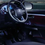 Toyota Fortuner interior dashboard view with infotainment system and illuminated city skyline through windshield