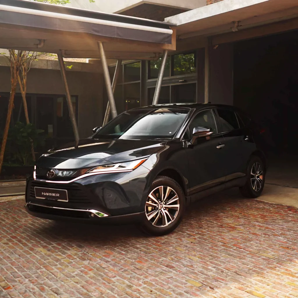 Toyota Harrier three-quarter front view in industrial warehouse setting with exposed steel beams and lighting
