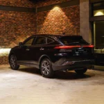 Black Toyota Harrier SUV parked in industrial garage with exposed brick walls and sleek alloy wheel design