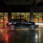 Black Toyota Harrier SUV positioned in contemporary glass showroom with architectural brick wall backdrop